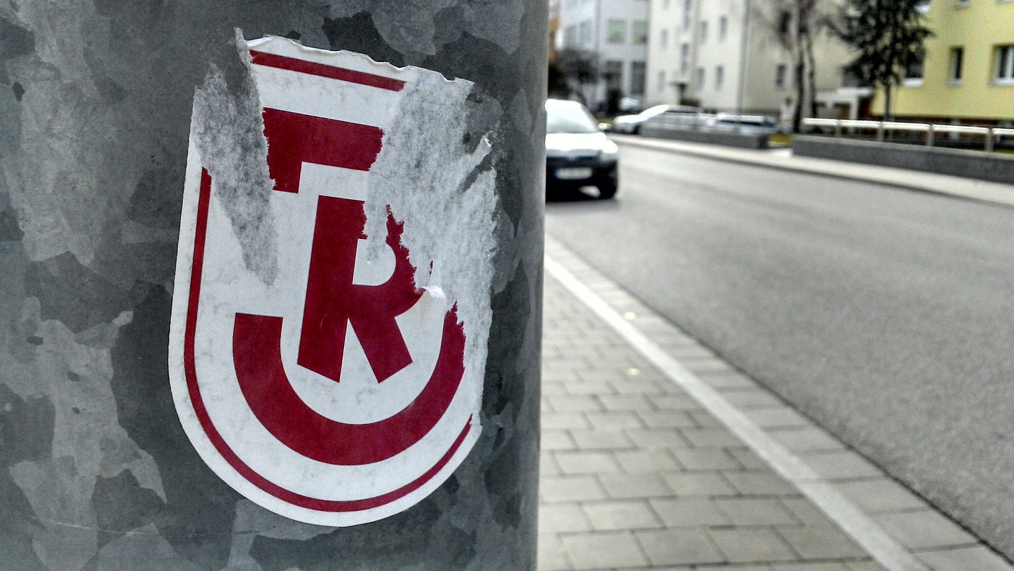 Archivbild: Ein halb abgerissener Aufkleber des SSV Jahn an einer Straßenlaterne