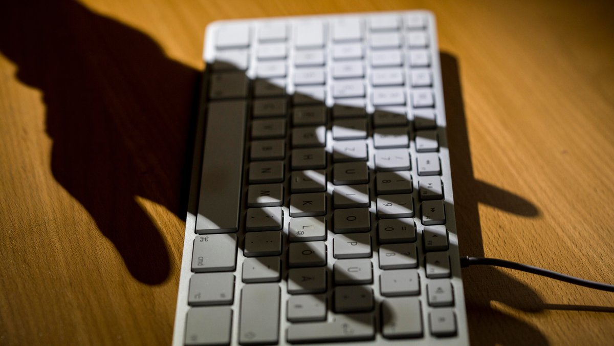 Schatten einer Hand auf einer Tastatur.