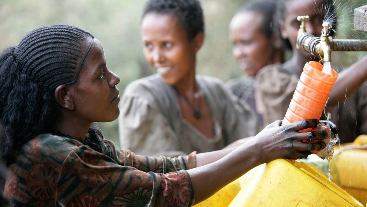 Frauen in Afrika befüllen Wasserkanister an einem von der UNICEF errichteten Brunnen.