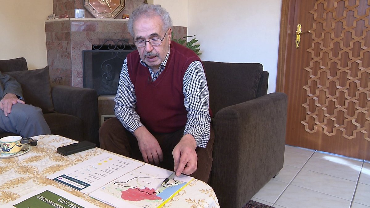 Adnan Wahhoud sitzt an einem Tisch und zeigt mit einem Stift auf eine Landkarte