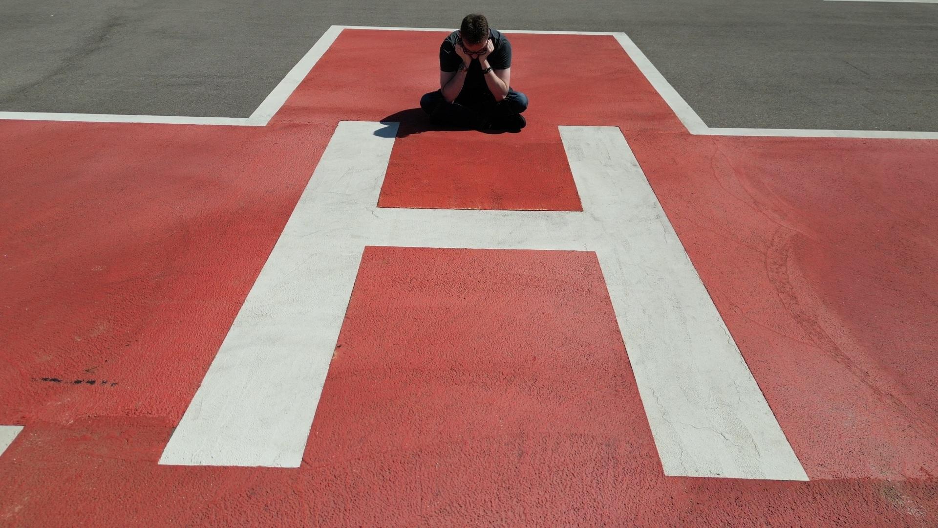 Tobias sitzt am Boden und hat den Kopf in seine Hände gelegt