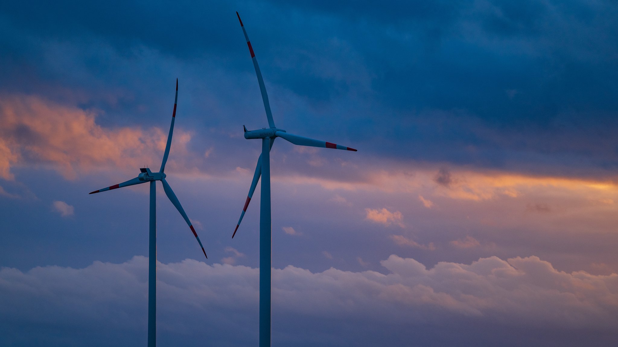 Zwei Windräder vor einem Wolkenhimmel