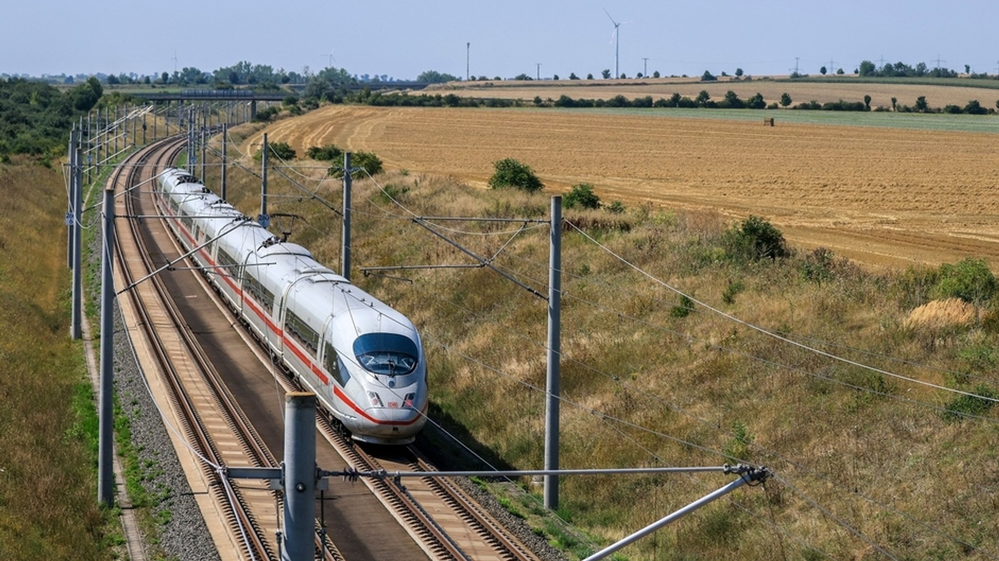 Ein ICE der Deutschen Bahn fährt zwischen abgeernteten Feldern.