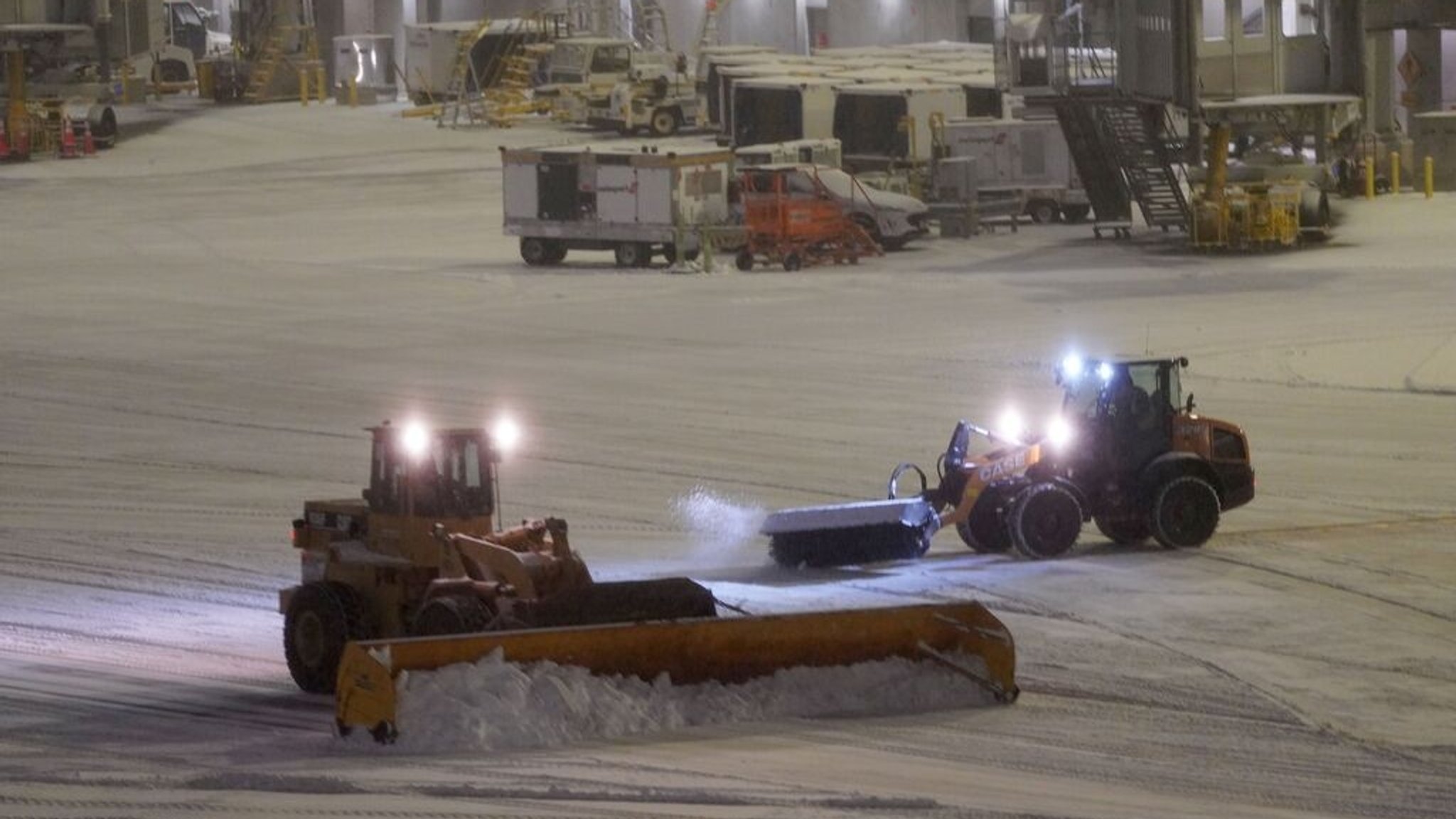 26.12.2025, USA, New York: Schneepflüge räumen das Vorfeld auf dem LaGuardia Airport. Wegen eines Wintersturms mit massivem Schneefall sind in der Ostküstenmetropole New York und der angrenzenden Region Hunderte Flüge gestrichen worden. Foto: Zhang Fengguo/XinHua/dpa +++ dpa-Bildfunk +++
