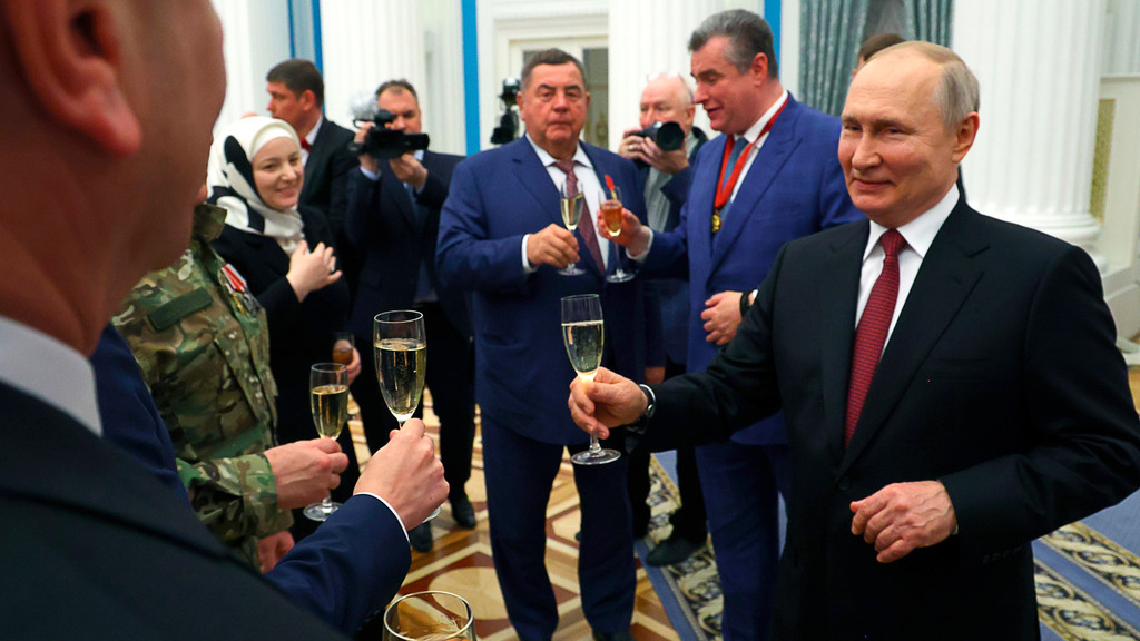 Der russische Präsident mit Sektglas prostet Gästen zu