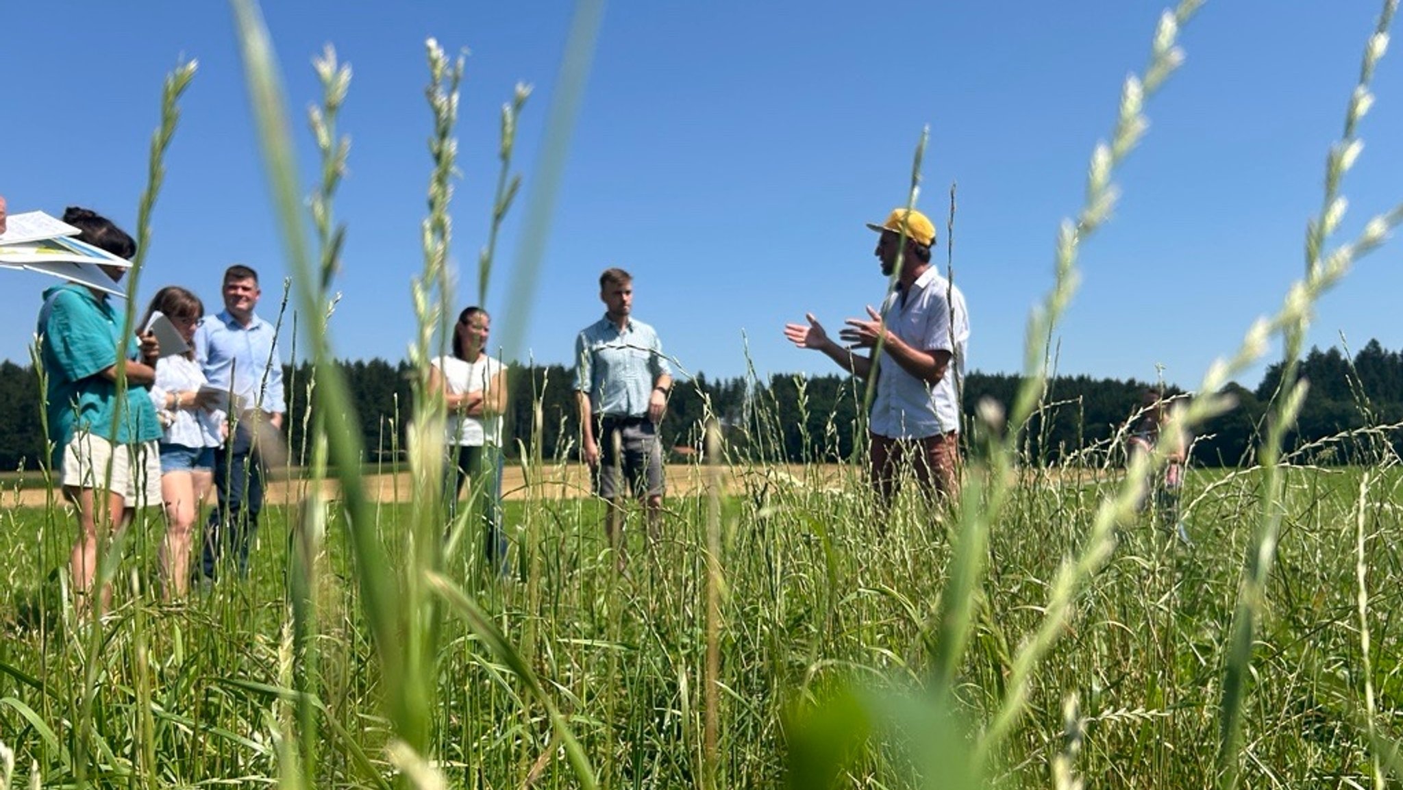 Ein Milchbauer erklärt den Teilnehmern der Erntepressefahrt seine Erntemethoden.