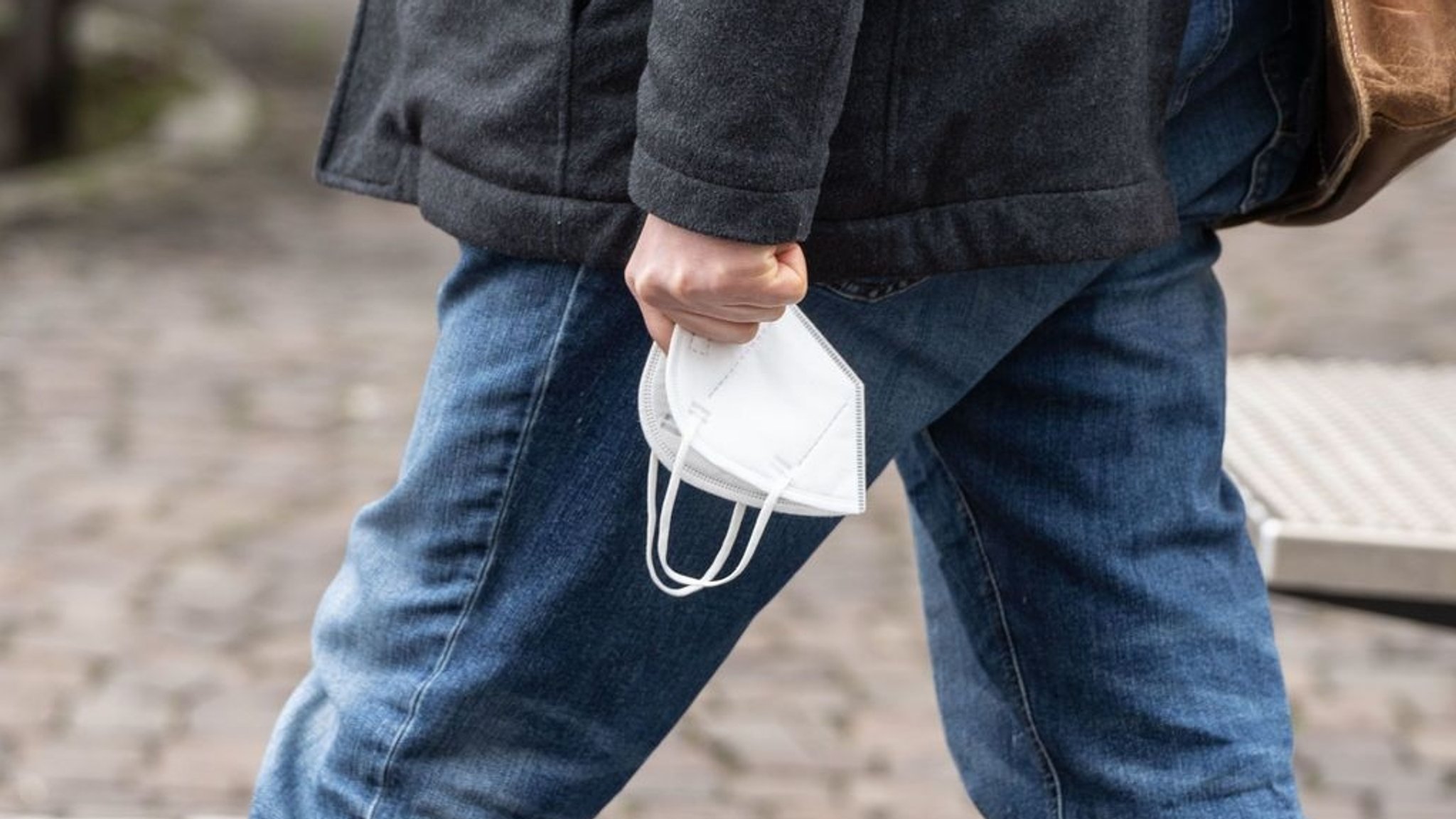 Ein Passant trägt seine FFP-2-Maske in der Hand.