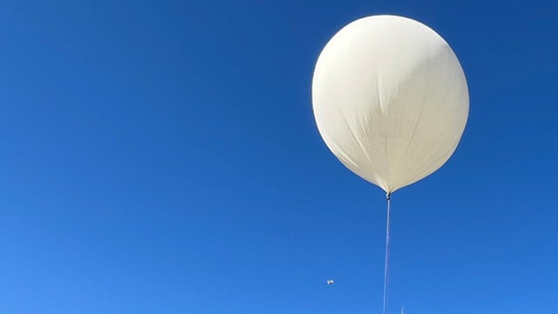 Ein weißer Ballon, im Hintergrund strahlend blauer Himmel.
