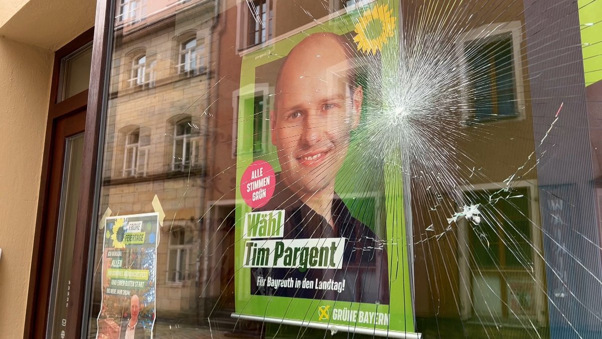 Hinter einer zersplitterten Schaufensterscheibe ist ein Wahlplakat mit dem Gesicht des Abgeordneten Tim Pargent zu erkennen.