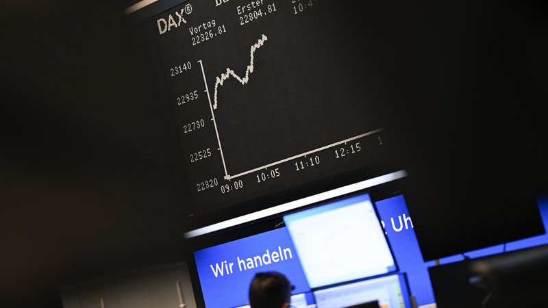 Ein Börsenhändler steht auf dem Parkett der Frankfurter Börse vor der Anzeiegtafel mit der Dax-Kurve an seinen Monitoren. | Bild: picture alliance/dpa | Arne Dedert Ein Börsenhändler steht auf dem Parkett der Frankfurter Börse vor der Anzeiegtafel mit der Dax-Kurve an seinen Monitoren.