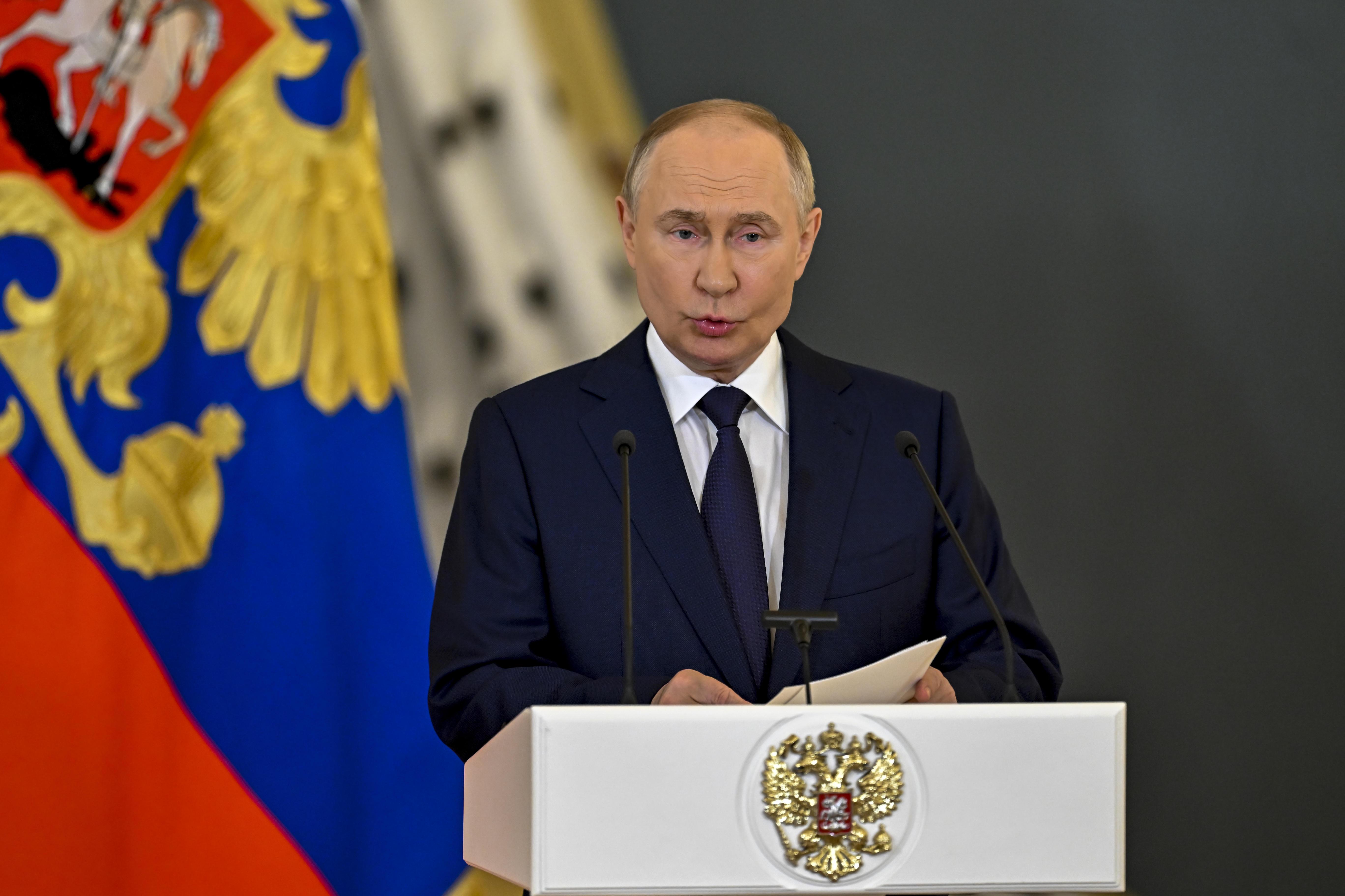 Der russische Präsident am Rednerpult mit Wappen und Flagge im Hintergrund