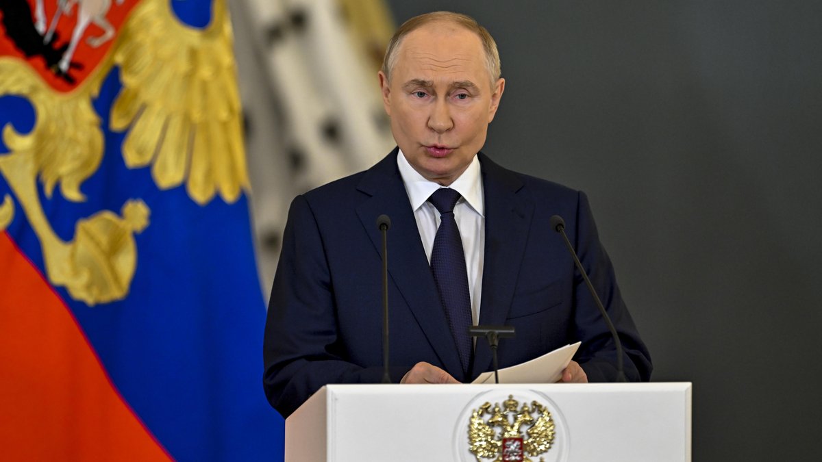 Der russische Präsident am Rednerpult mit Wappen und Flagge im Hintergrund
