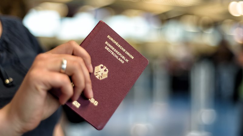 Eine Frau hält einen deutschen Reisepass in der Hand.