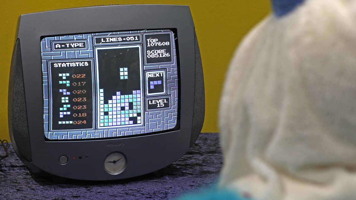 Ein verkleideter Messebesucher spielt auf der Gamescom im Retrospielebereichw das Spiel "Tetris"