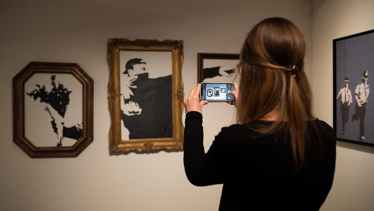 Eine Besucherin fotografiert eine Reproduktion von Banksy. 