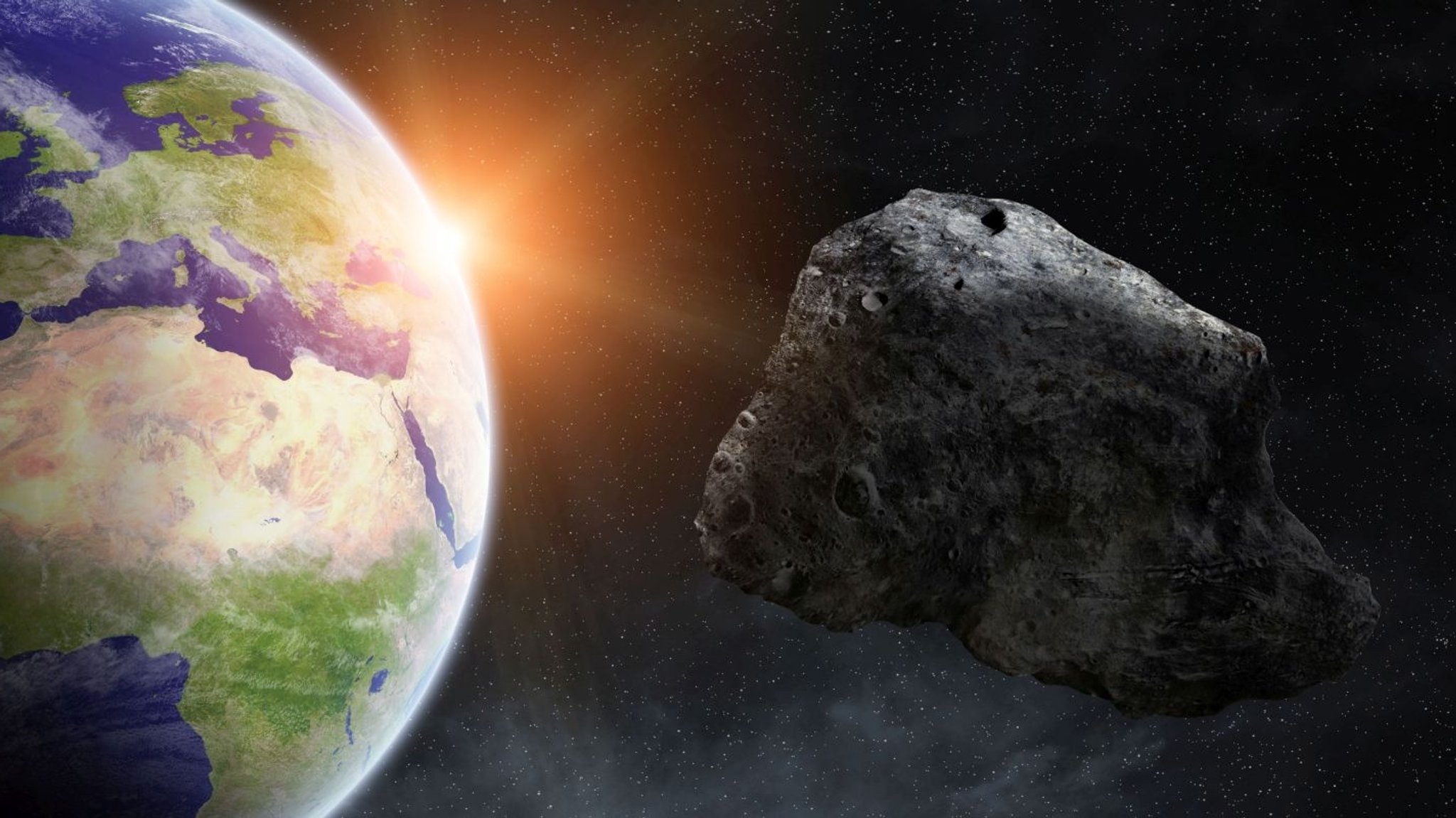 Künstlerische Darstellung: Asteroid fliegt an Erde vorbei. Tausende Asteroiden kreisen um die Sonne - und hin und wieder kommt einer auch in die Nähe der Erde.