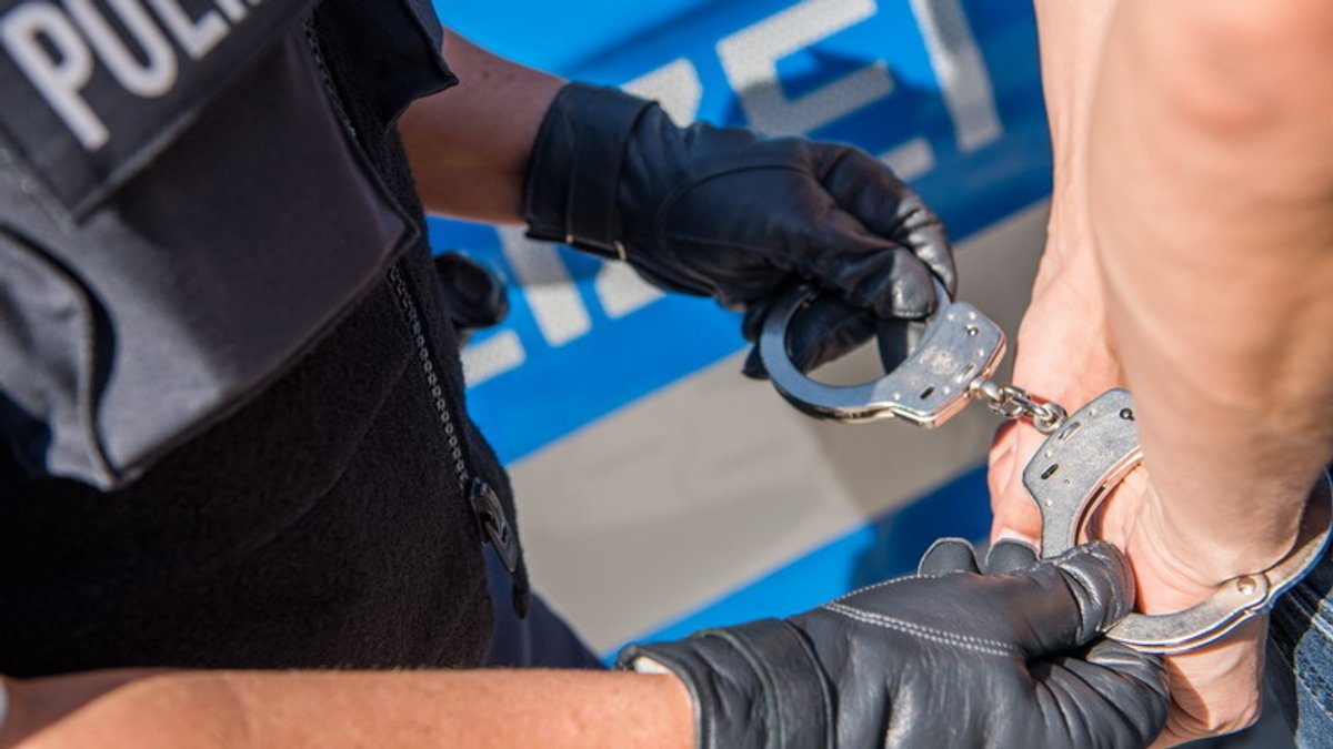 Ein Polizist legt einer Person Handschellen an (Symbolbild).