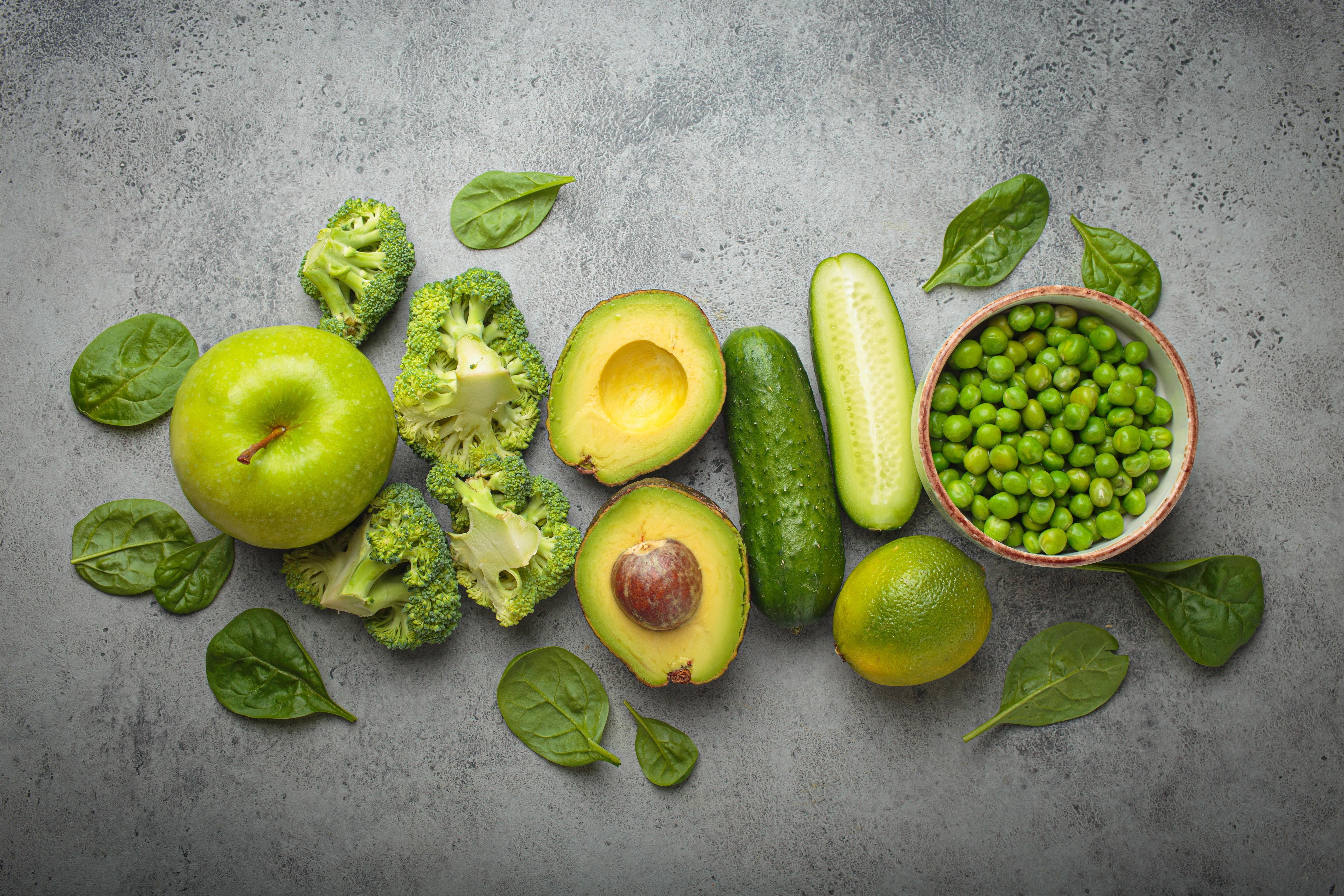 Äpfel, Brokkoli, Avocados, Gurken und grüne Erbsen, appetitlich angerichtet auf einem Tisch