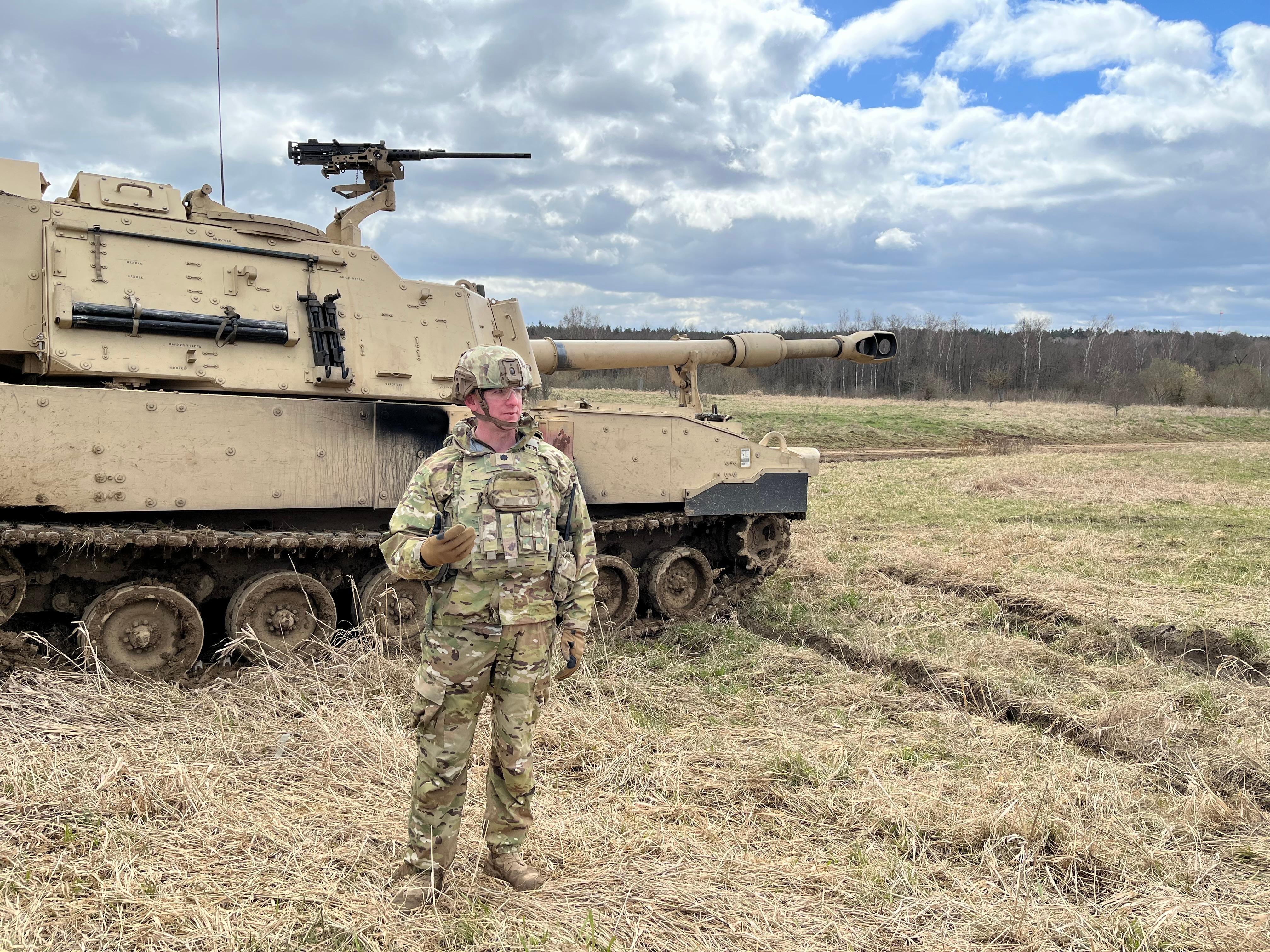 Ein Soldat steht vor einer Panzerhaubitze