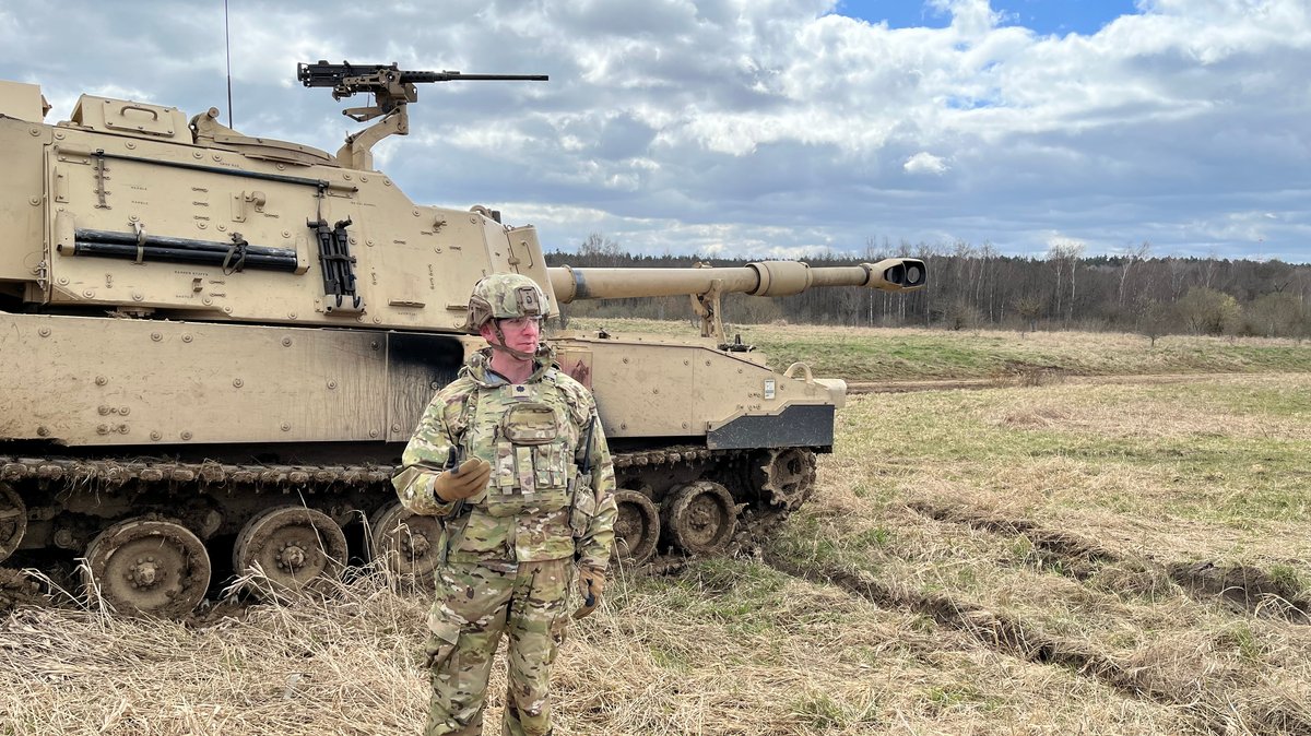 Ein Soldat steht vor einer Panzerhaubitze