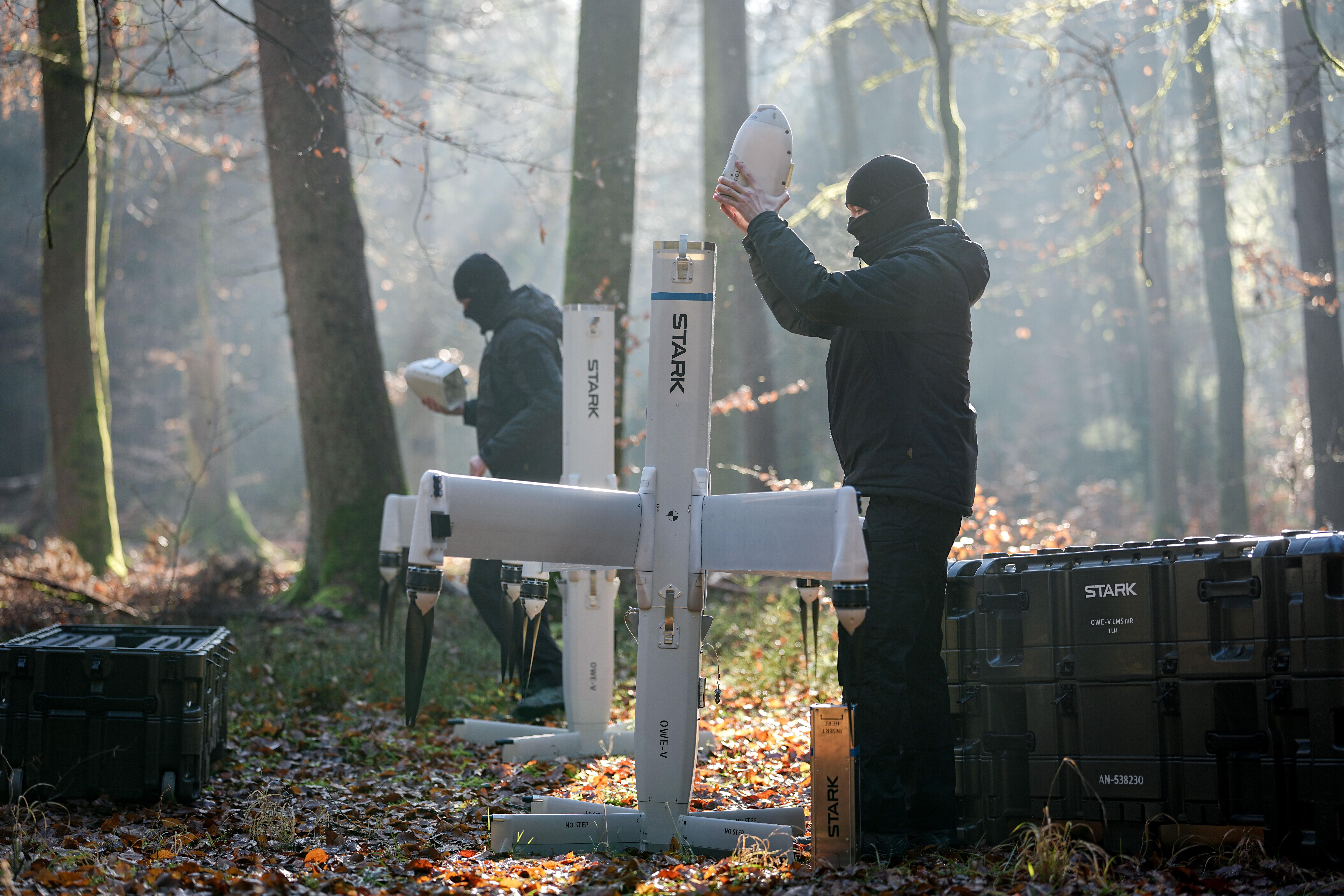 Zwei Männer stehe vor einer Drohne und bauen diese zusammen.