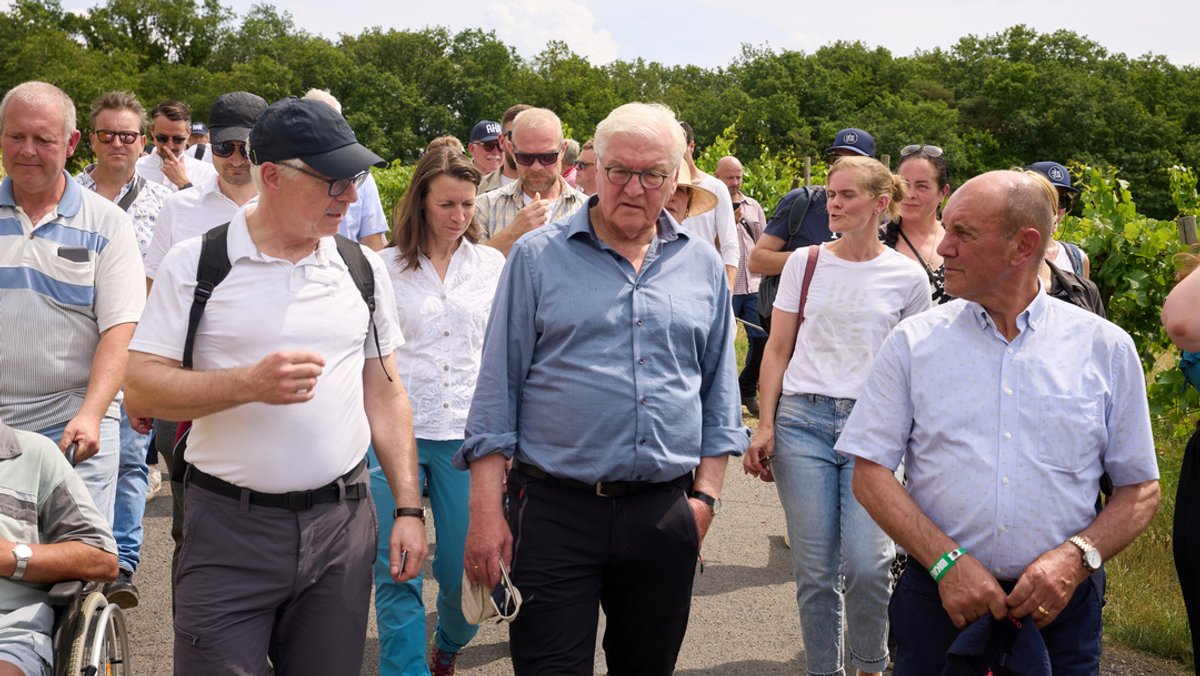 Bundespräsident Frank-Walter Steinmeier (M.) spricht während seiner Wanderung über den Rotweinwanderweg im Ahrtal mit Anwohnern.