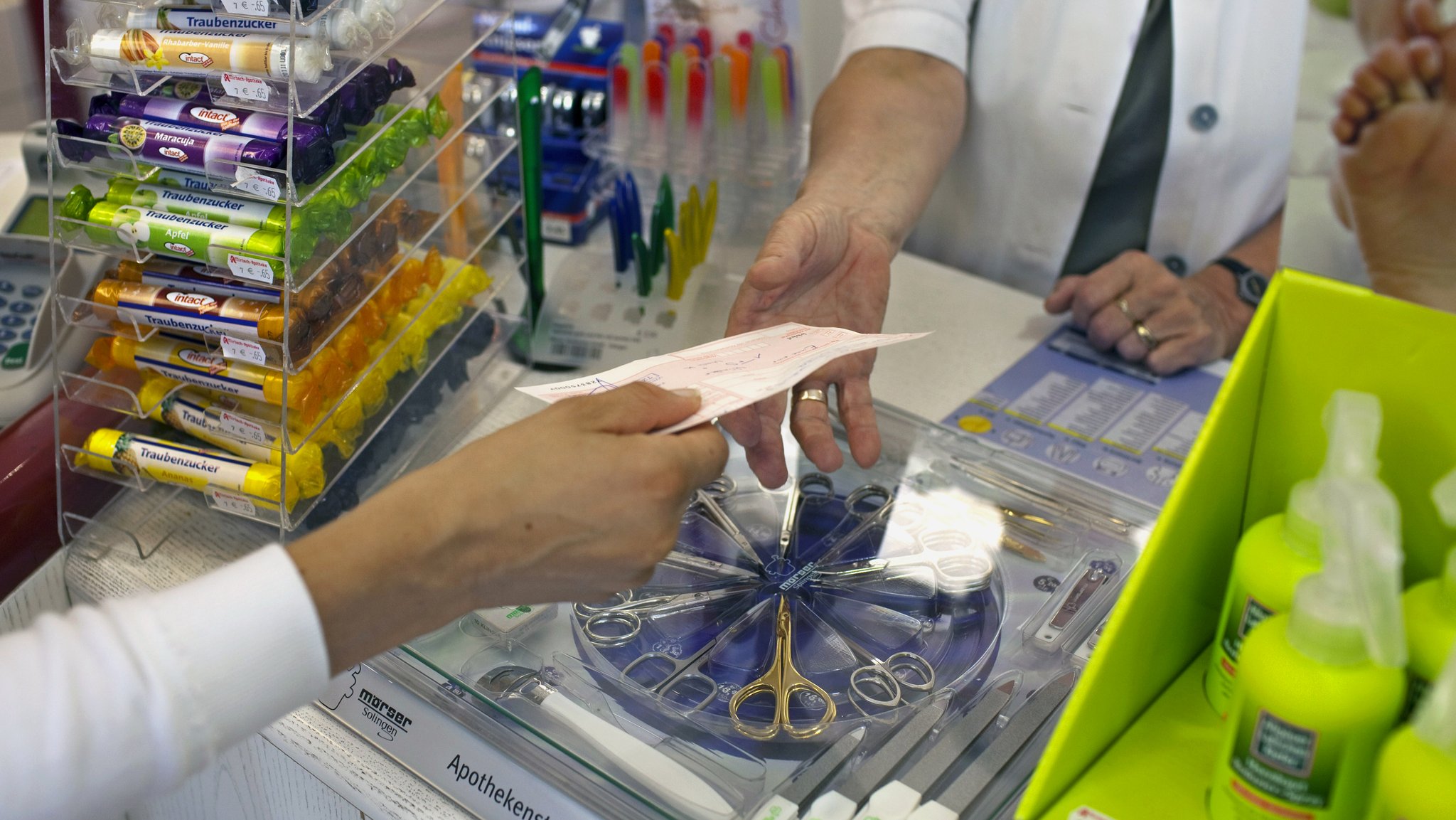 Eine Kundin gibt in einer Apotheke ein ärztliches Rezept ab, um verschriebene Medikamente zu erhalten.