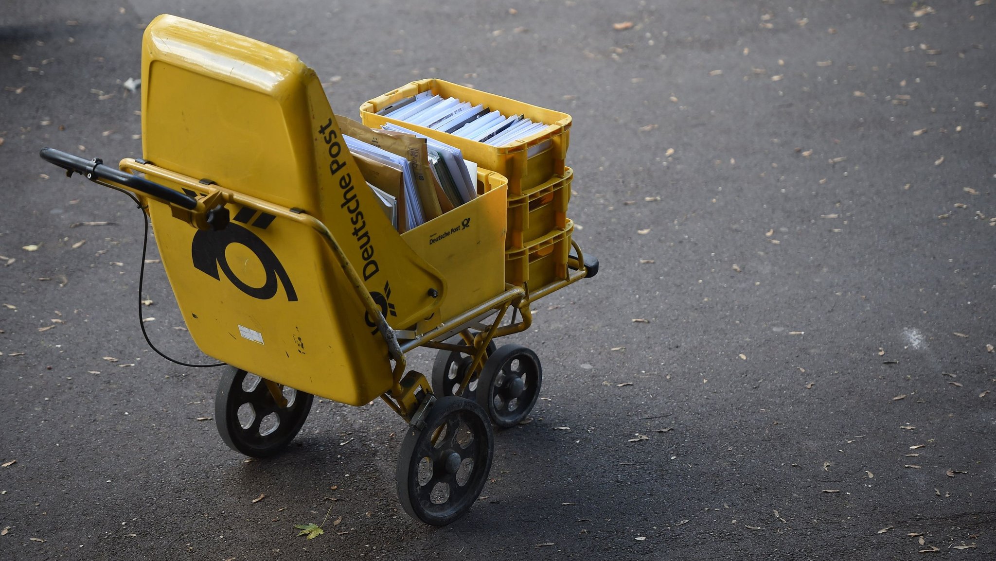 Der Trolley eines Zustellers der Deutschen Post steht auf der Straße (Symbolbild)