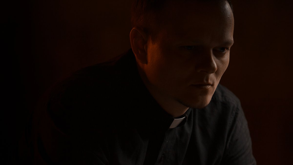 Priester in dunklem Raum.