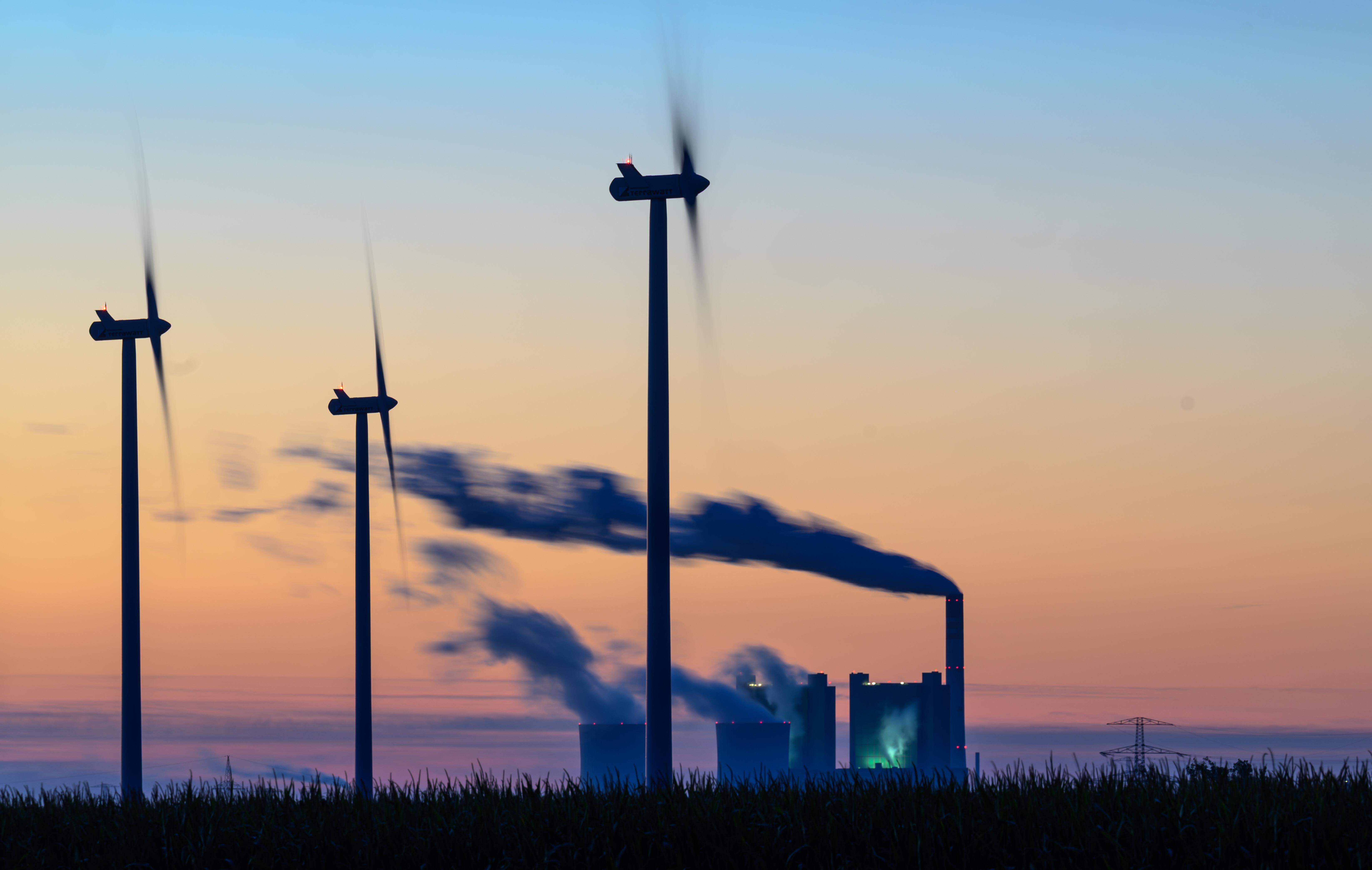 Symbolbild: Windräder drehen sich vor der Kulisse des Braunkohlekraftwerkes Schkopau.