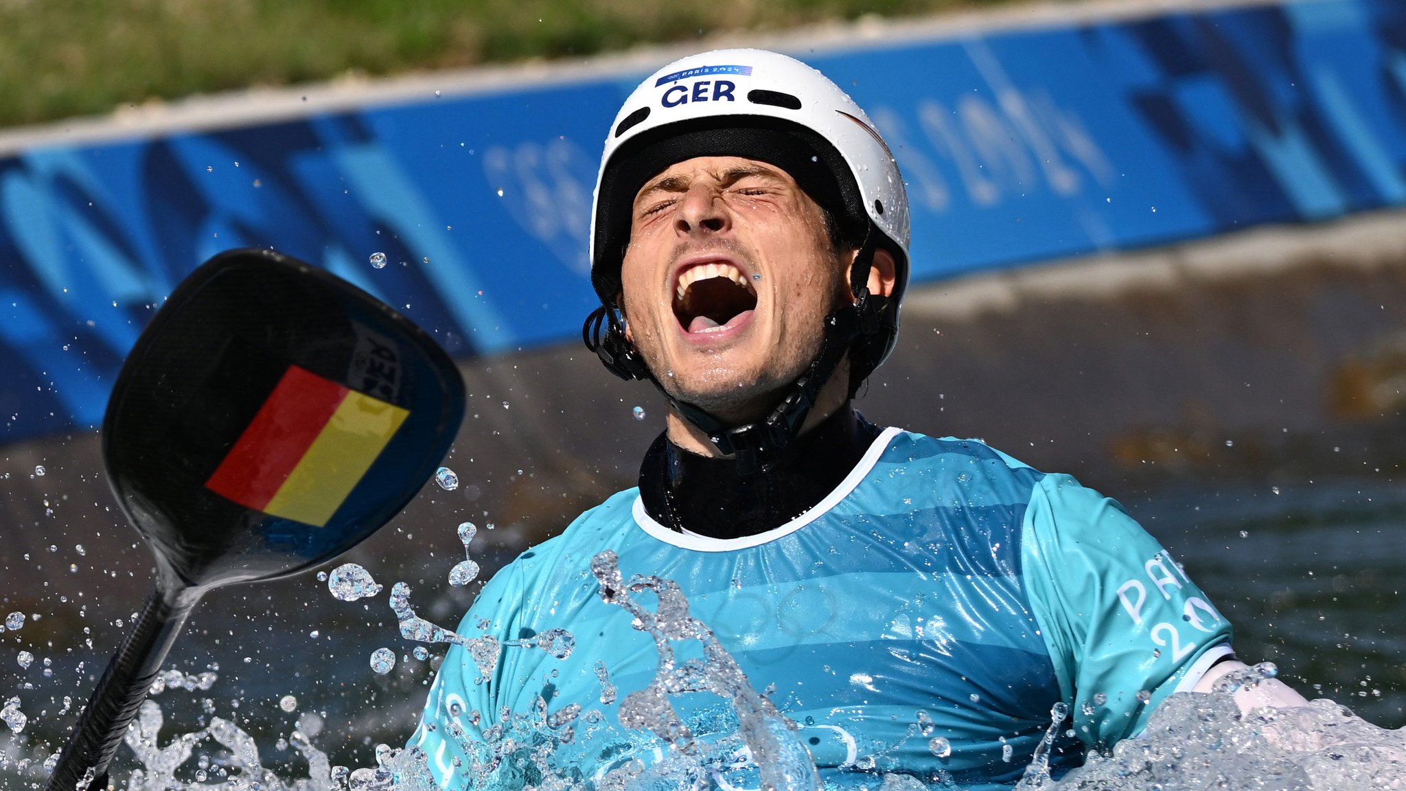 Der Augsburger Kanut Noah Hegge jubelt im Pariser Wildwasserkanal, nachdem er im Kajak Cross die Bronzemedaille gewonnen hat.