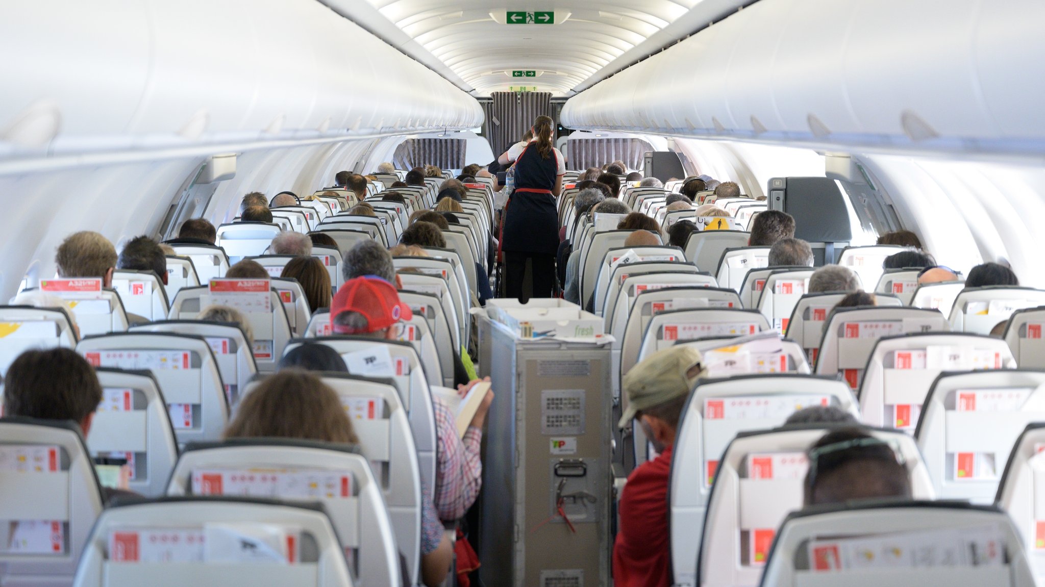 Eine Flugbegleiterin verteilt in einem Airbus Speisen und Getränke an die Passagiere (Archivbild).