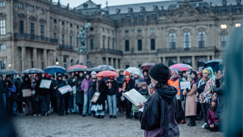 Am Kiliansbrunnen vor der Residenz Würzburg haben sich Menschen versammelt, im Rahmen der Queerfeministischen Aktionstage. | Bild: Demokratie leben/Wechselkurs Bildung e.V. Am Kiliansbrunnen vor der Residenz Würzburg haben sich Menschen versammelt, im Rahmen der Queerfeministischen Aktionstage.