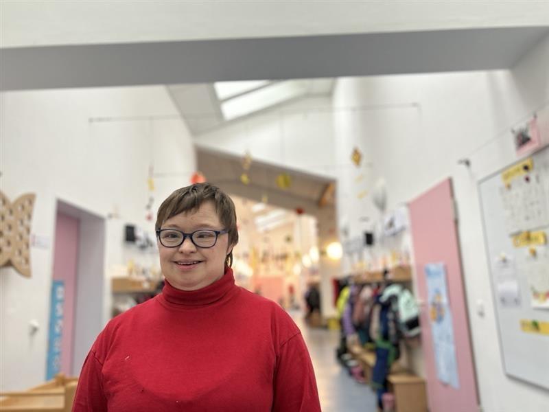 Eine Frau mit Brille und rotem Pullover lächelt in die Kamera.