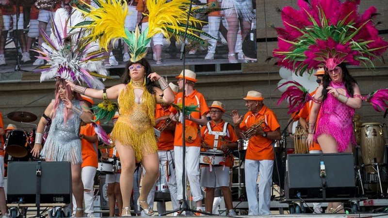 Frauen in bunten Samba-Kostümen und Trommler auf einer Bühne beim Samba-Festival 2023.