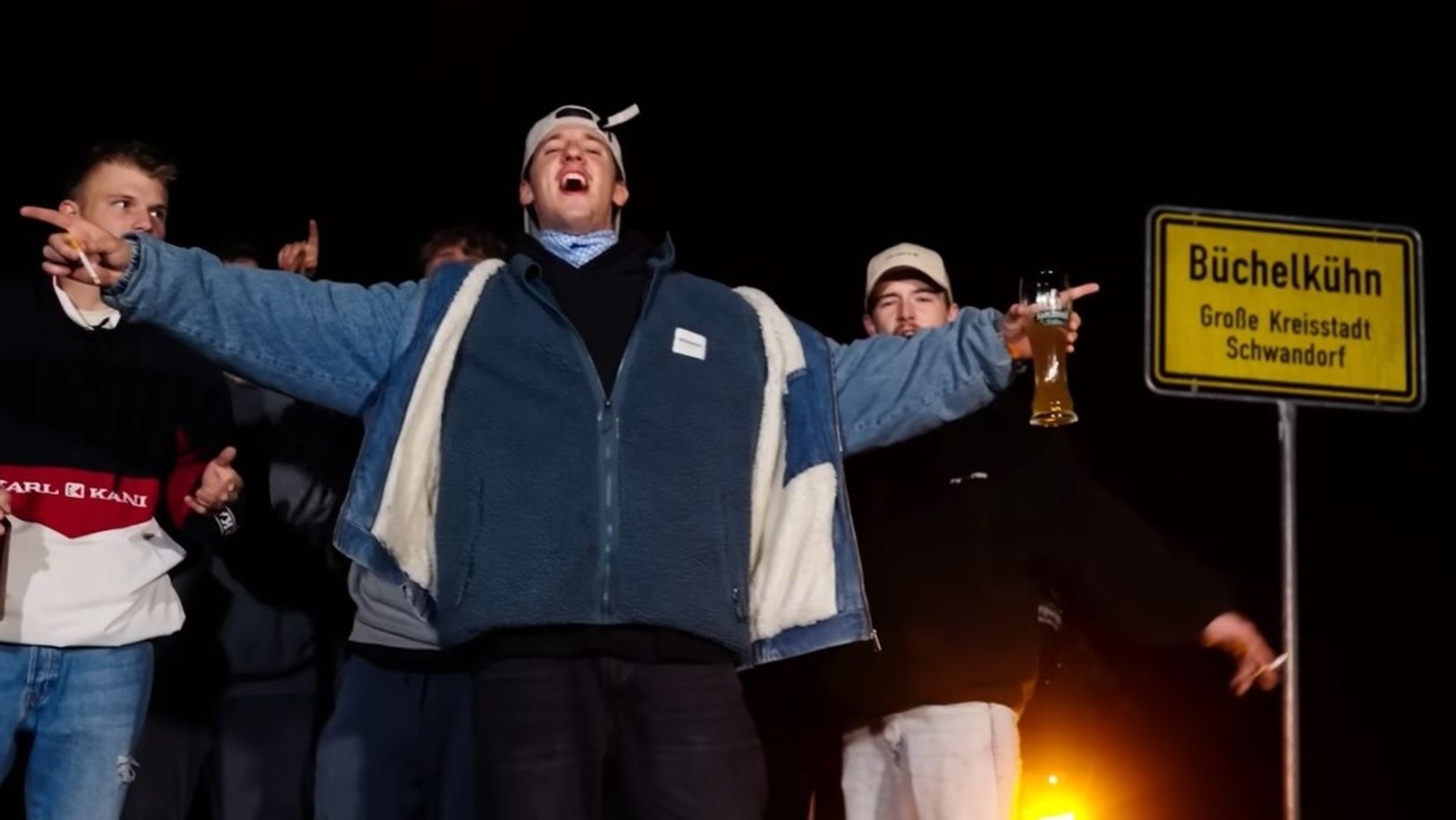 Der Rapper Tream posiert vor dem Ortschild von Büchelkühn