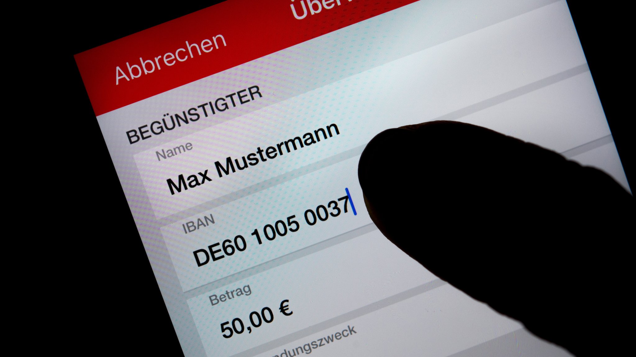 Eine Frau nutzt auf ihrem Smartphone eine App, um im Online-Banking eine SEPA-Überweisung zu veranlassen (gestellte Szene)