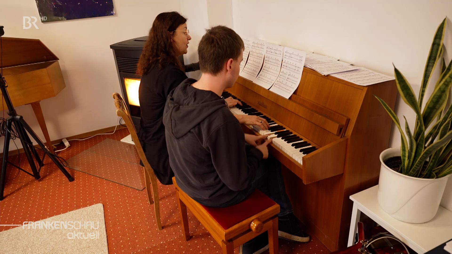 Ein Mann und eine Frau sitzen an einem Klavier.