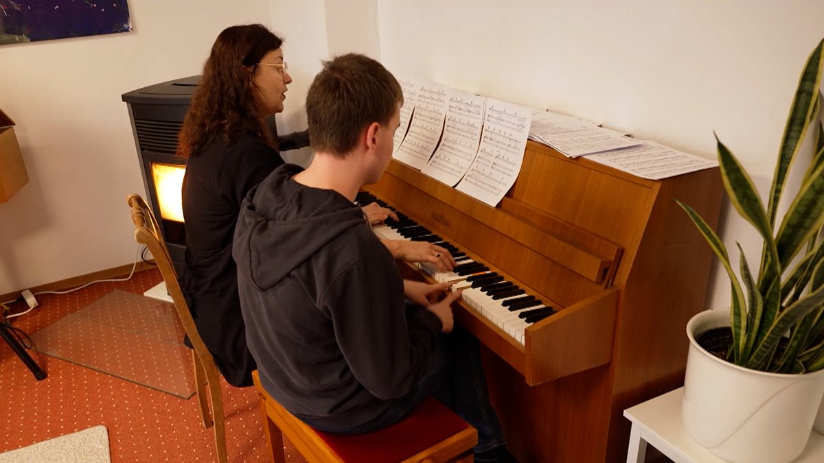 Ein Mann und eine Frau sitzen an einem Klavier.