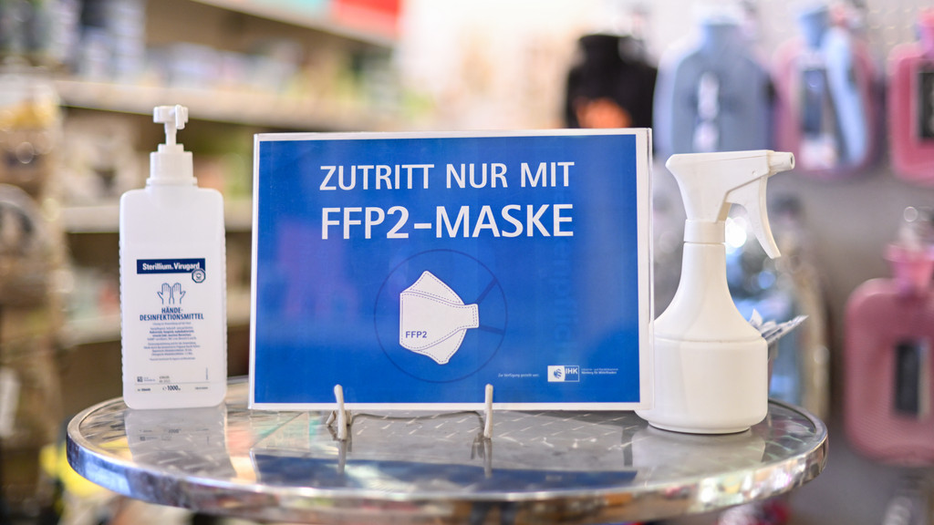 Ein Hinweisschild mit der Aufschrift "Zutritt nur mit FFP2-Maske" steht zusammen mit Desinfektionsmittel in einem Haushaltswarenladen.