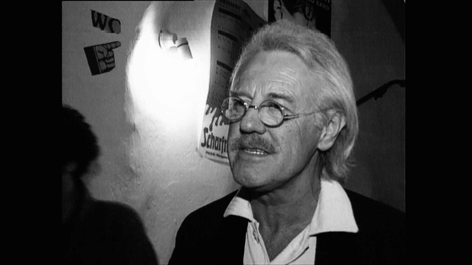 Ein Mann mit grauen Haaren und runder Brille