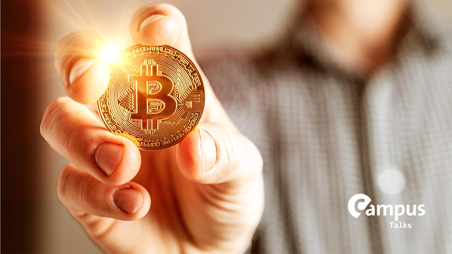 Goldene leuchtende Bitcoin Münze in der Hand eines Mannes
