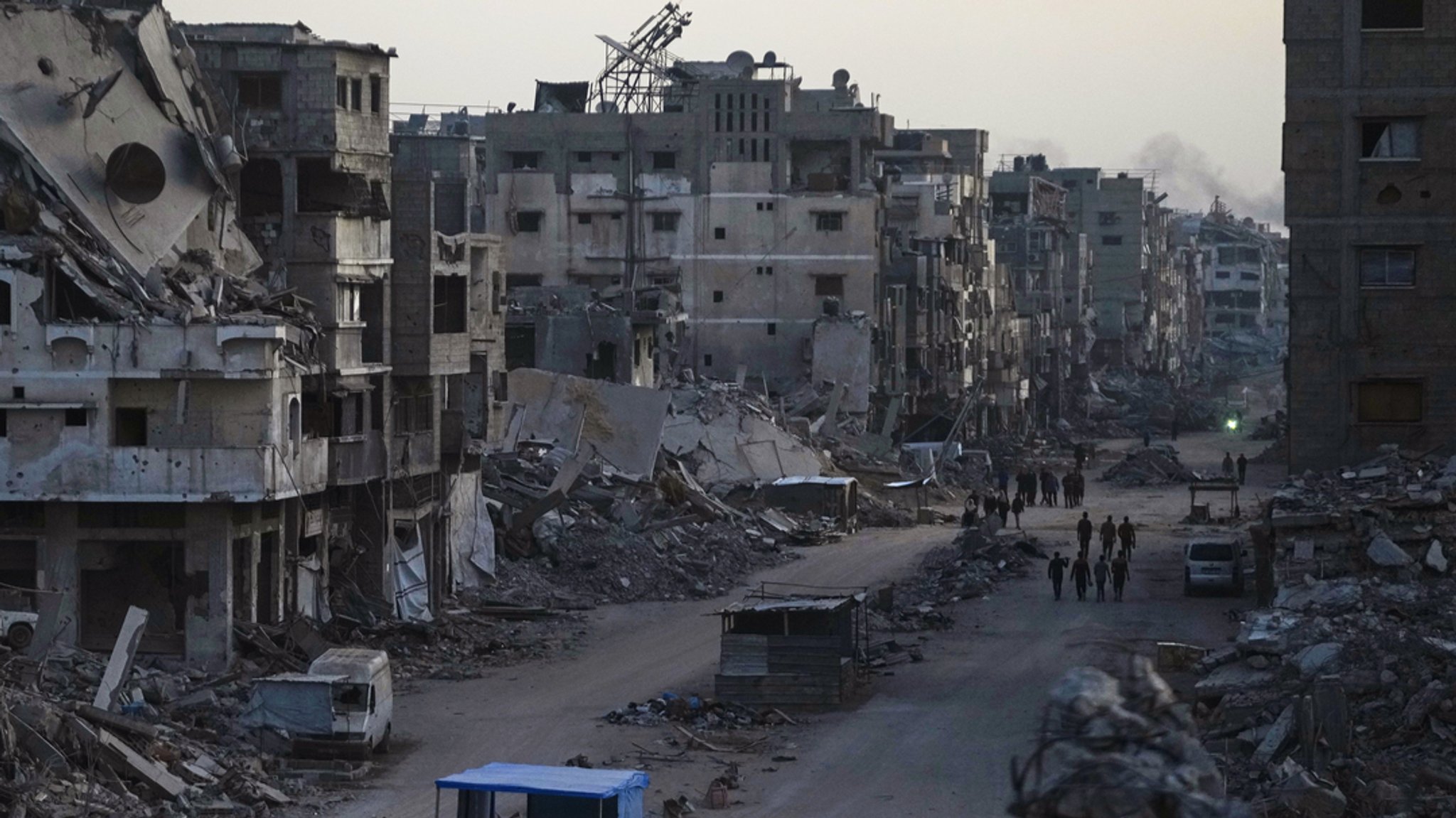 22.10.2025, Palästinensische Gebiete, Gaza: Palästinenser gehen durch die Zerstörung nach der israelischen Luft- und Bodenoffensive im Viertel Sheikh Radwan in Gaza. 