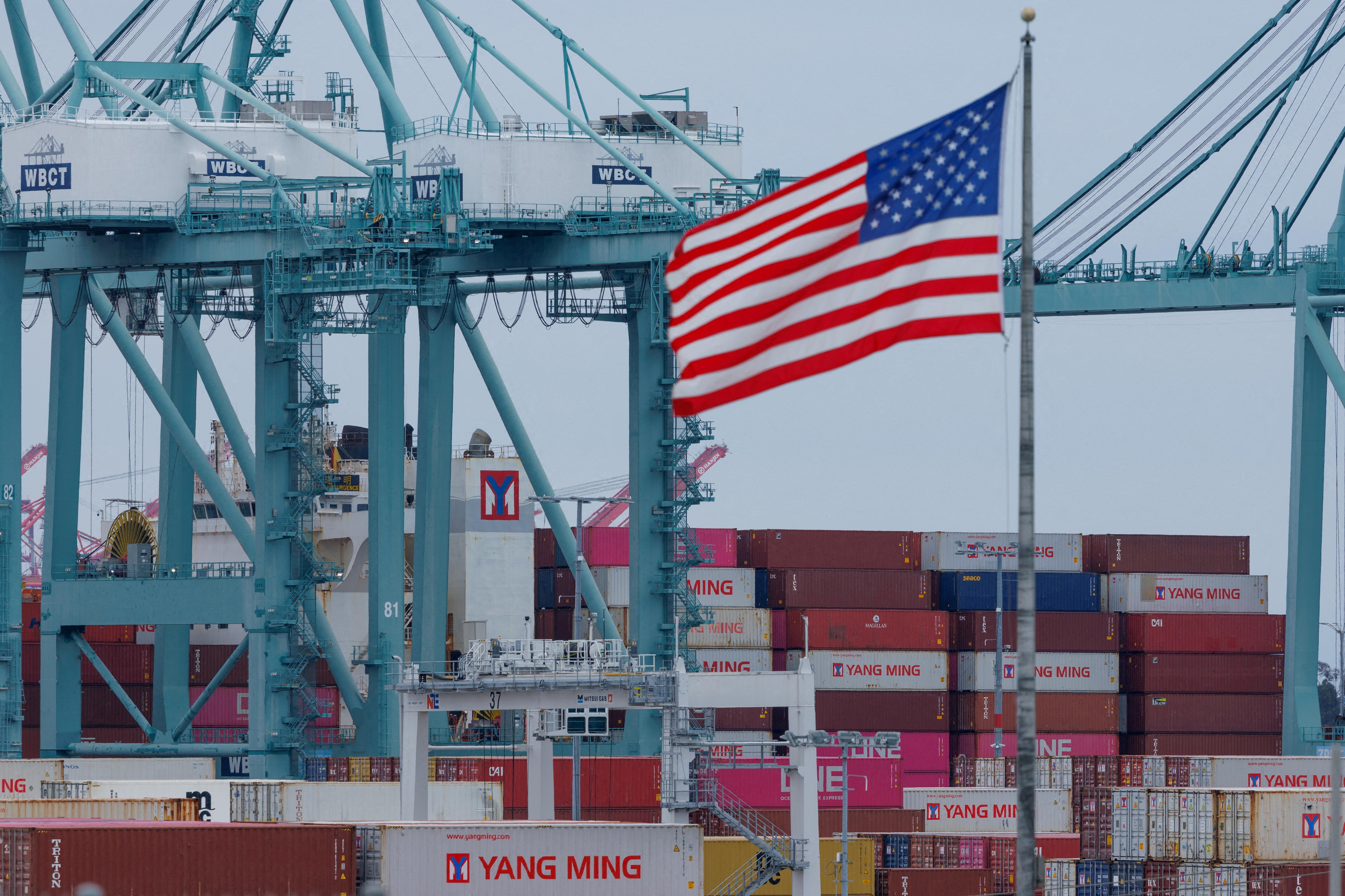 Eine US-Flagge weht vor Schiffscontainern am Hafen von Los Angeles.