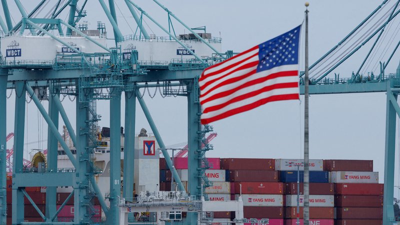 Eine US-Flagge weht vor Schiffscontainern am Hafen von Los Angeles. | Bild: Reuters Eine US-Flagge weht vor Schiffscontainern am Hafen von Los Angeles.
