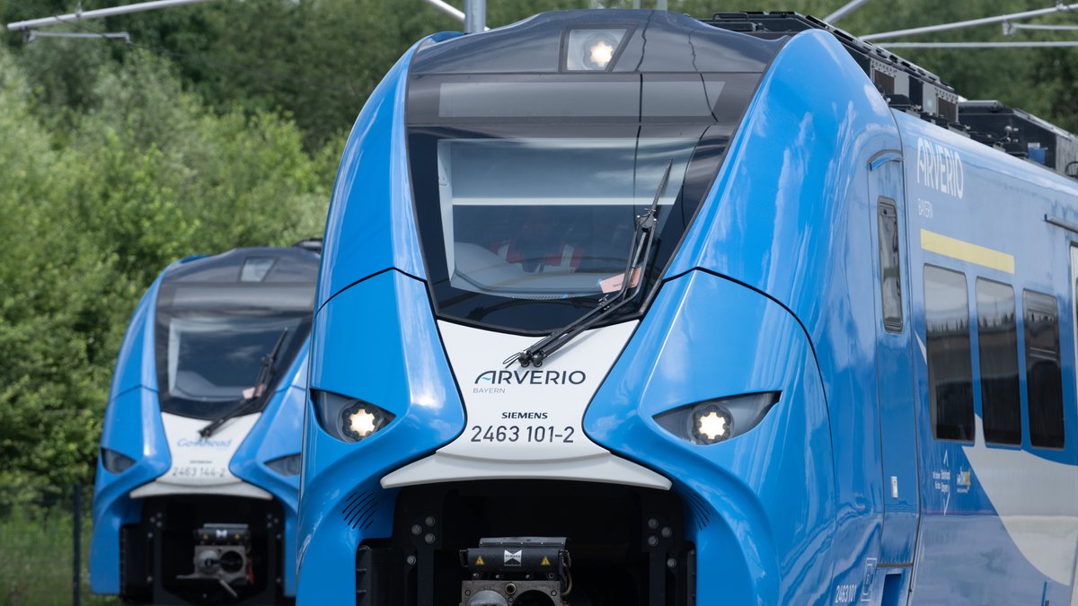 In einem Betriebswerk steht ein Triebwagen vom Typ Siemens Mireo mit dem Schriftzug "Arverio Bayern", dahinter ein Zug mit der Aufschrift "Go-Ahead. 