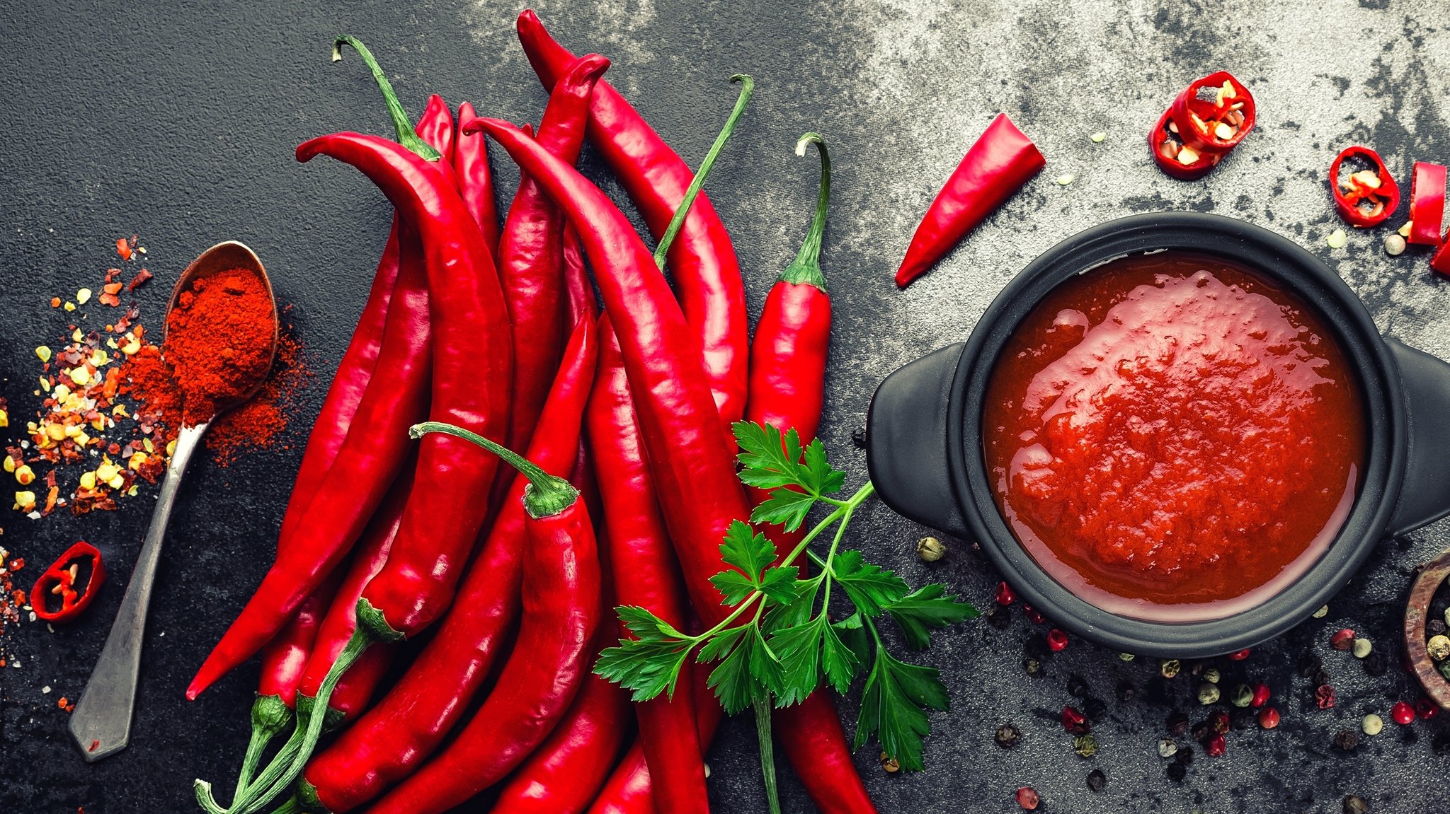 Flatlay von Chili Sauce mit Chilis und Pfeffer.
