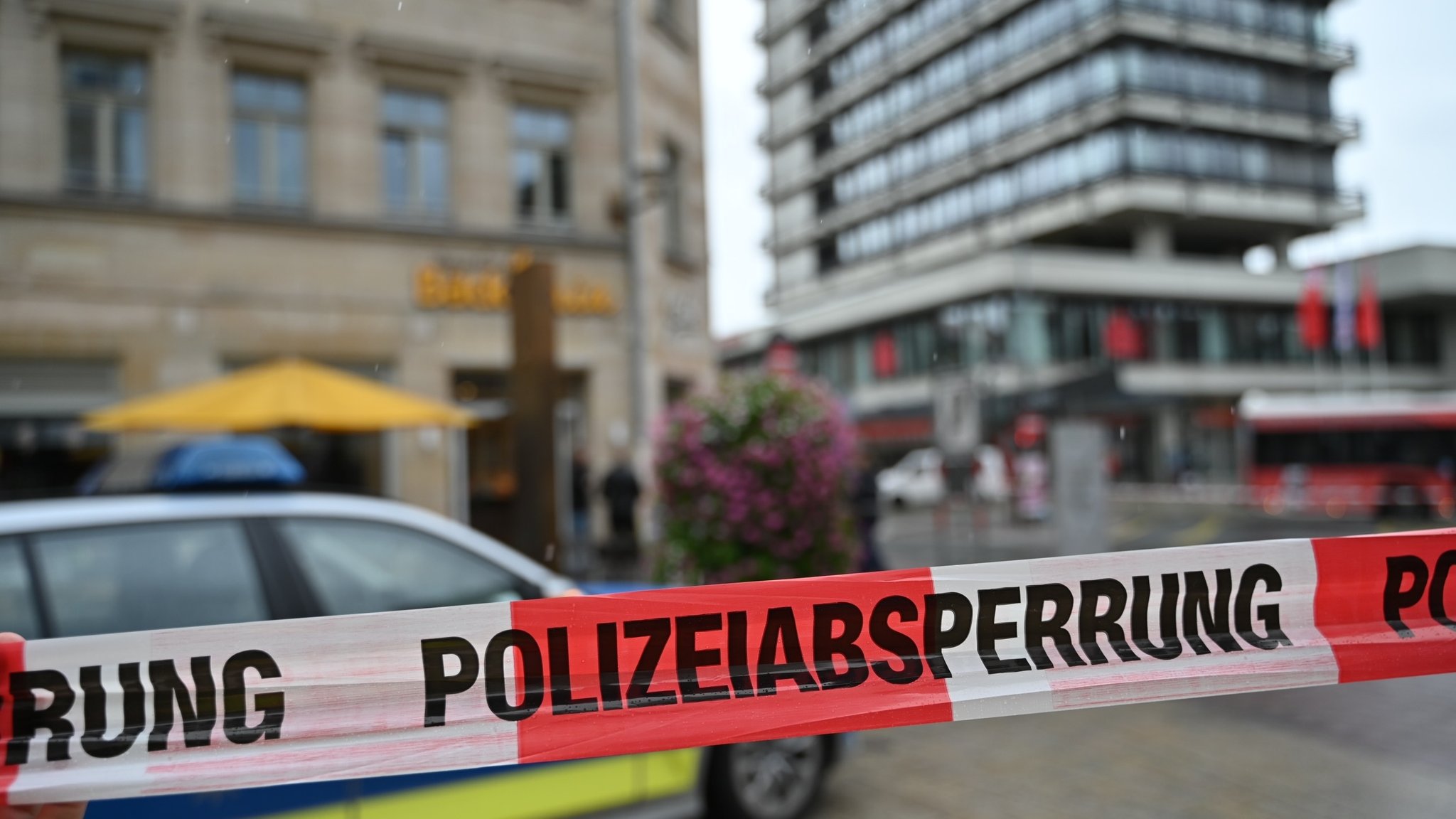 Rot-weißes Absperrband mit der Aufschrift "Polizeiabsperrung", im Hintergrund eine Bäckerei und ein Hochhaus in Fürth.