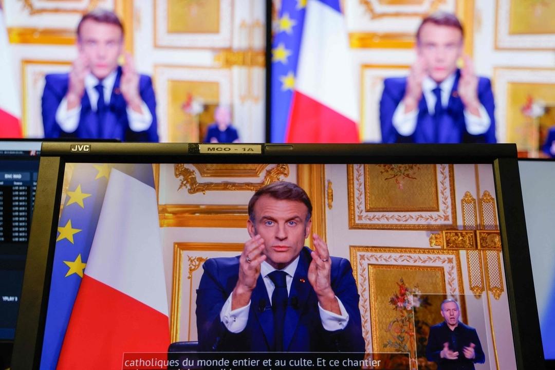 05.12.2024, Frankreich, Paris: Der französische Präsident Emmanuel Macron ist auf Monitoren in einem Kontrollraum im AFP-Hauptquartier zu sehen, als er sich während einer Fernsehübertragung aus dem Elysee-Palast an die Nation wendet.