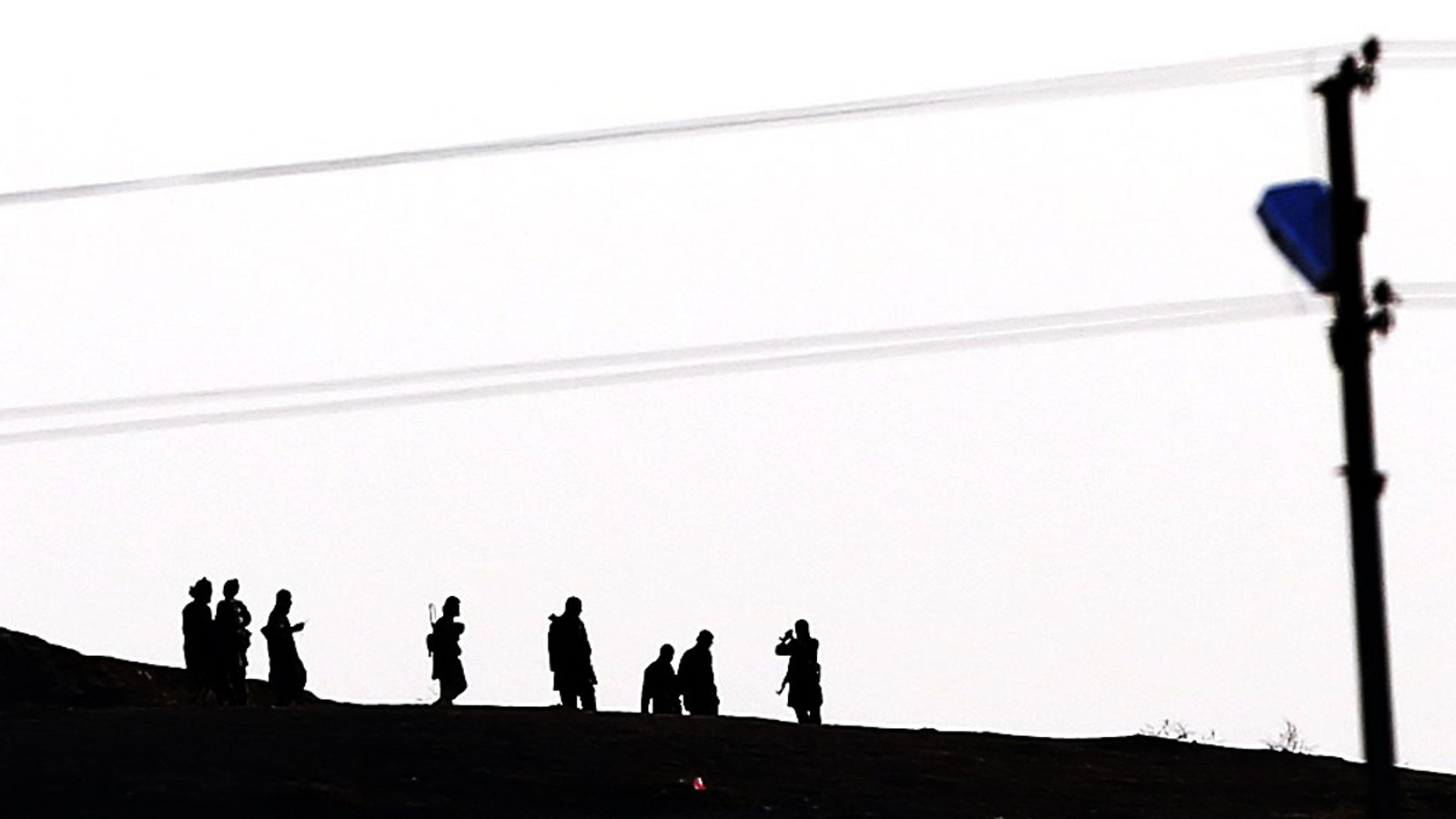 Kämpfer des Islamischen Staates auf einer Anhöhe gehend im Gegenlicht fotografiert (Symbolbild).